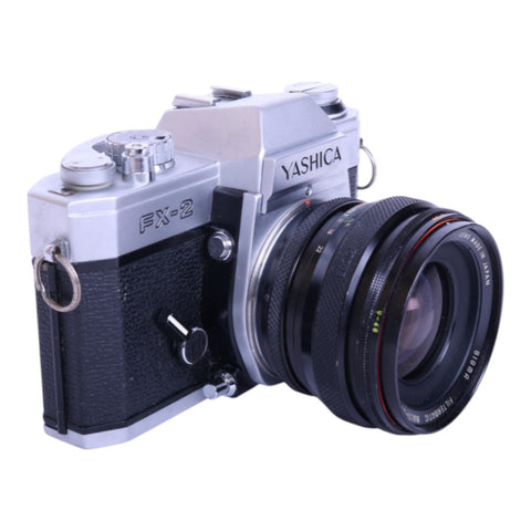 Yashica FX-2 analoge spiegelreflexcamera, zilver/zwart, met Sigma Filtermatic 24mm f/2.8 lens, schuin van voren, tweedehands