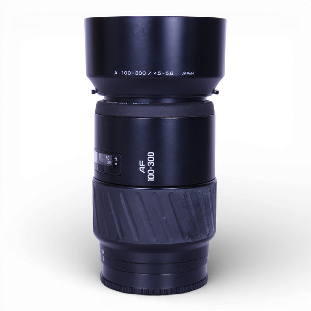 Minolta AF 100-300mm f/4.5-5.6 telezoomlens, zwart, lens rechtop met de zonnekap erop, tweedehands